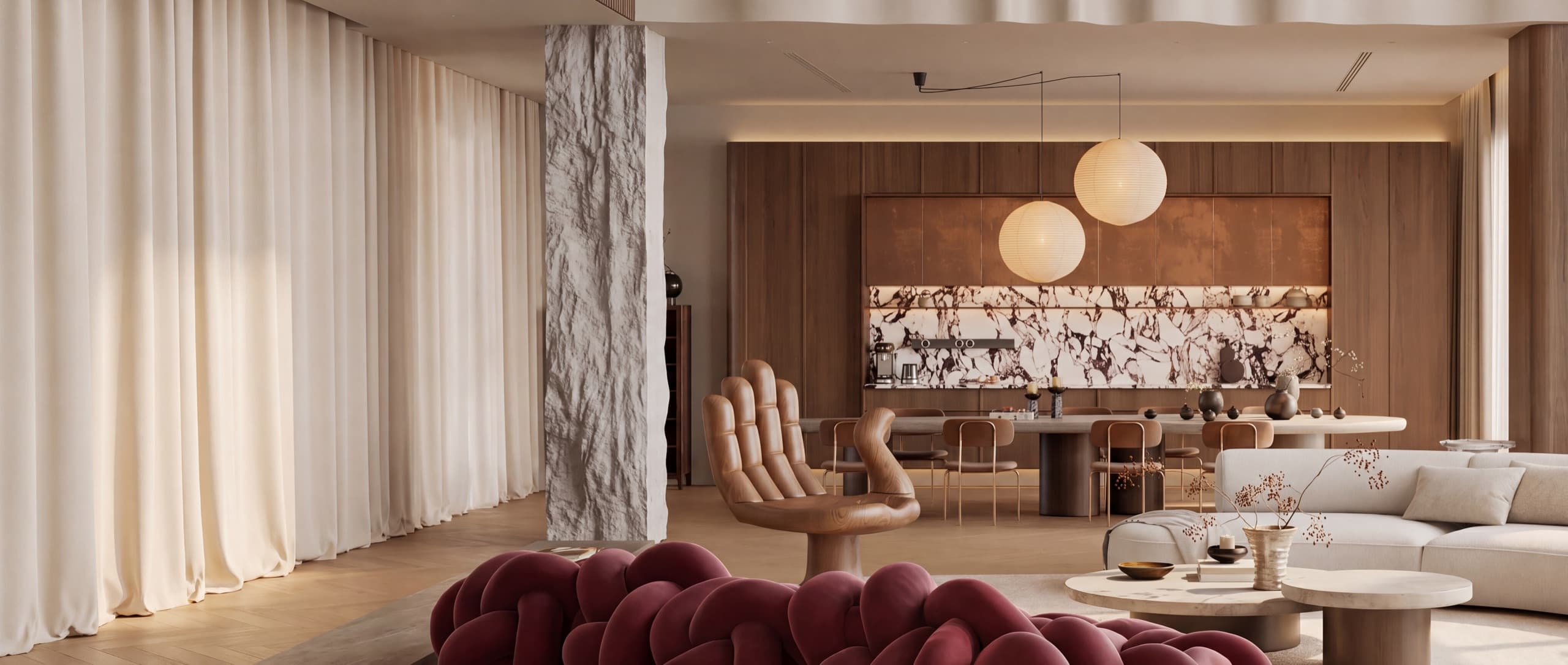 Living and dining area with a burgundy sculptural sofa and marble kitchen