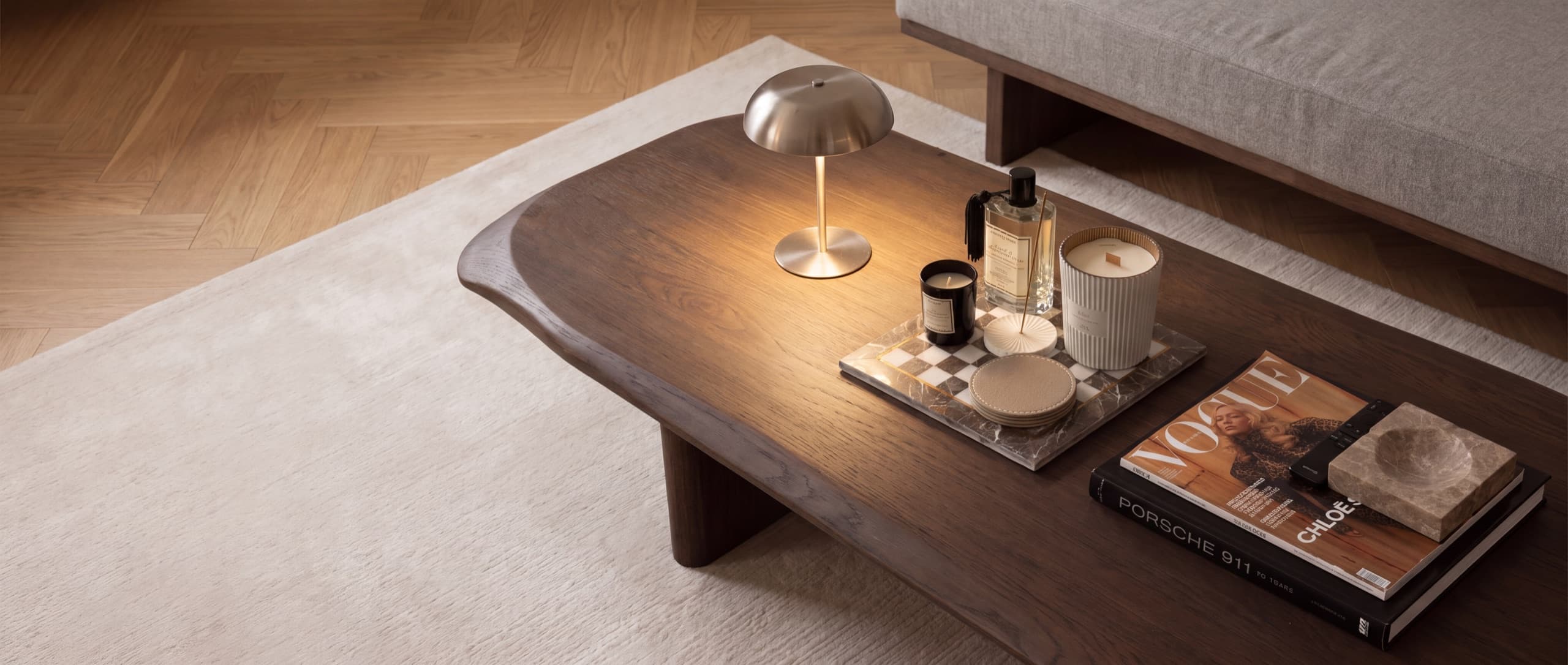 Coffee table styled with a lamp, candles, and magazines