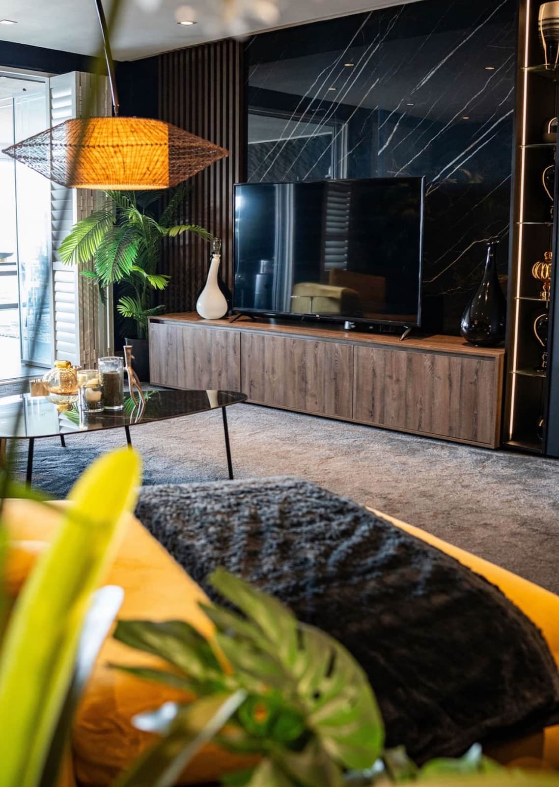 Moody living room with a dark marble feature wall and rattan pendant lamp