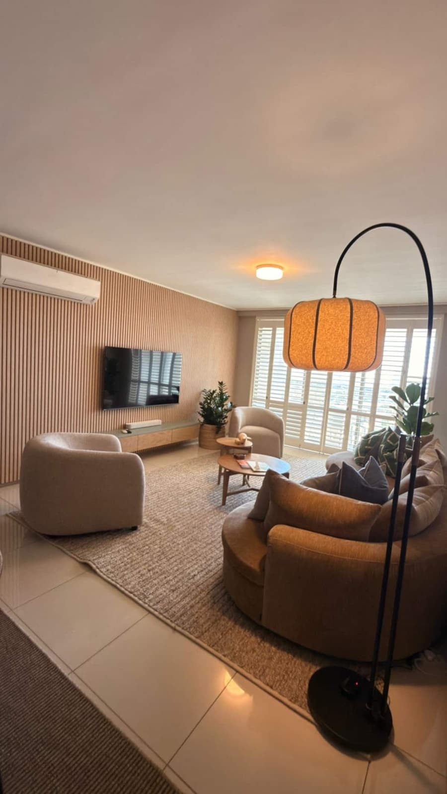 Warm living room with a mustard sofa, rattan panelled wall, and floor lamp